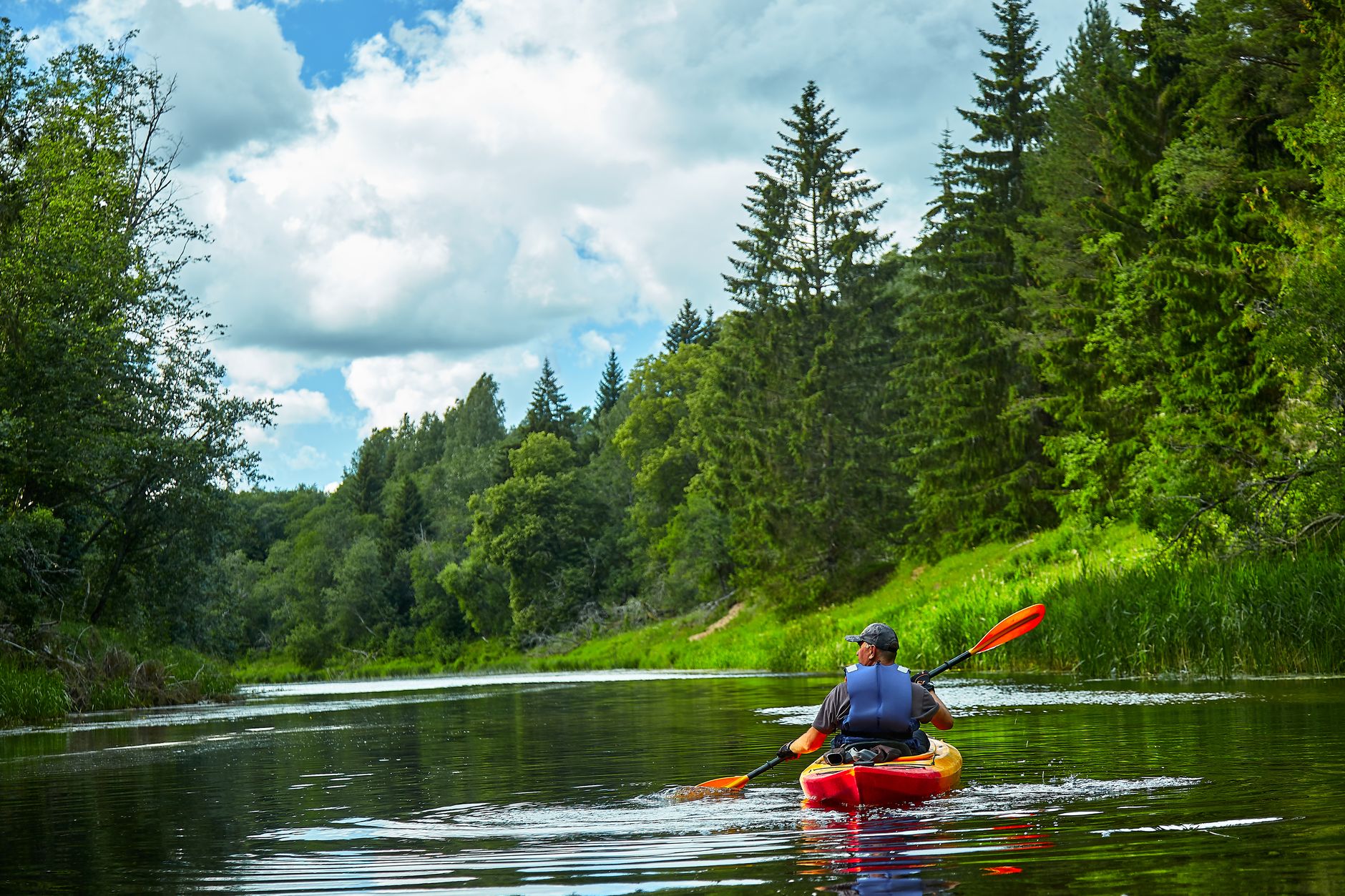 man riding on red kayak on river