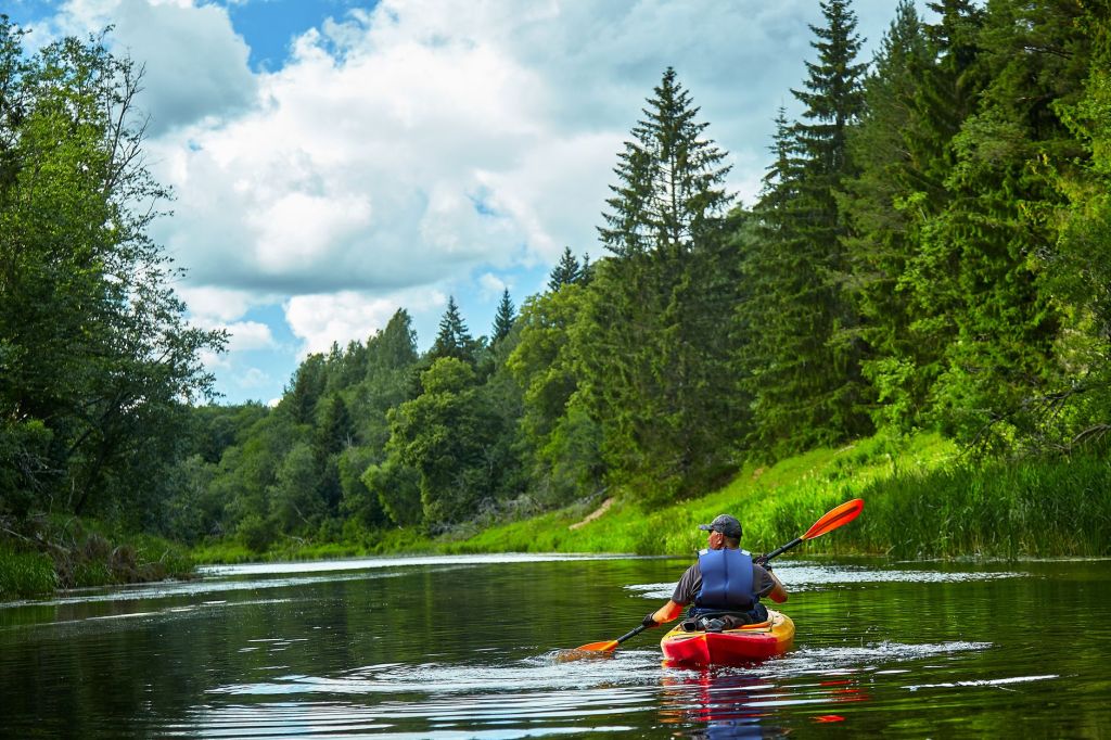 man riding on red kayak on river