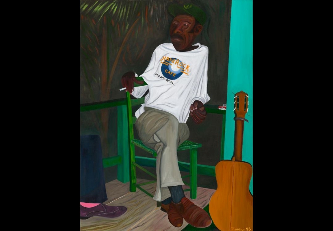 A man wearing a "Jack's Cafe" t-shirt sits on a green chair, holding a guitar, in a tropical setting with palm trees.