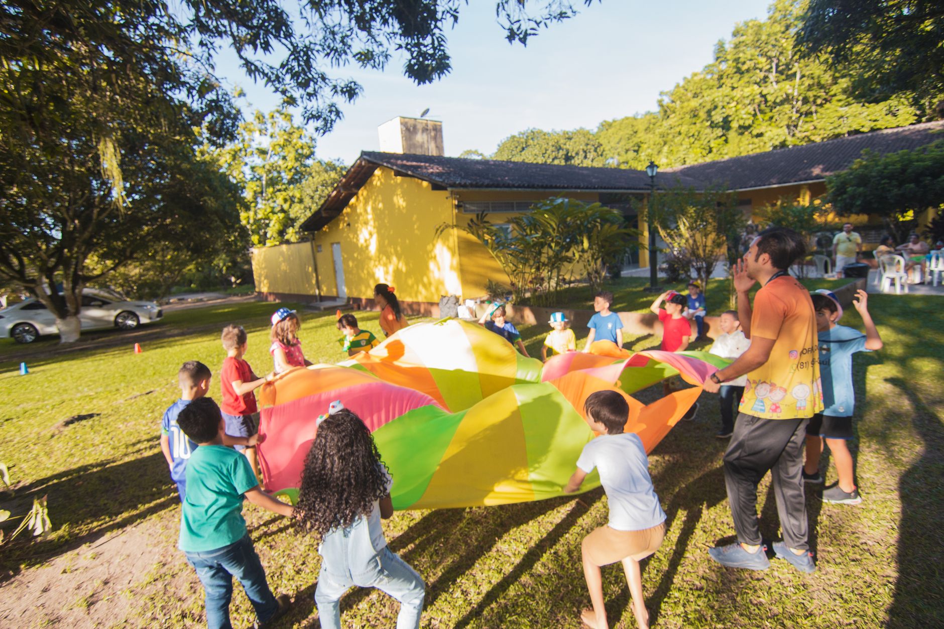 children playing with a colorful parachute in the yard