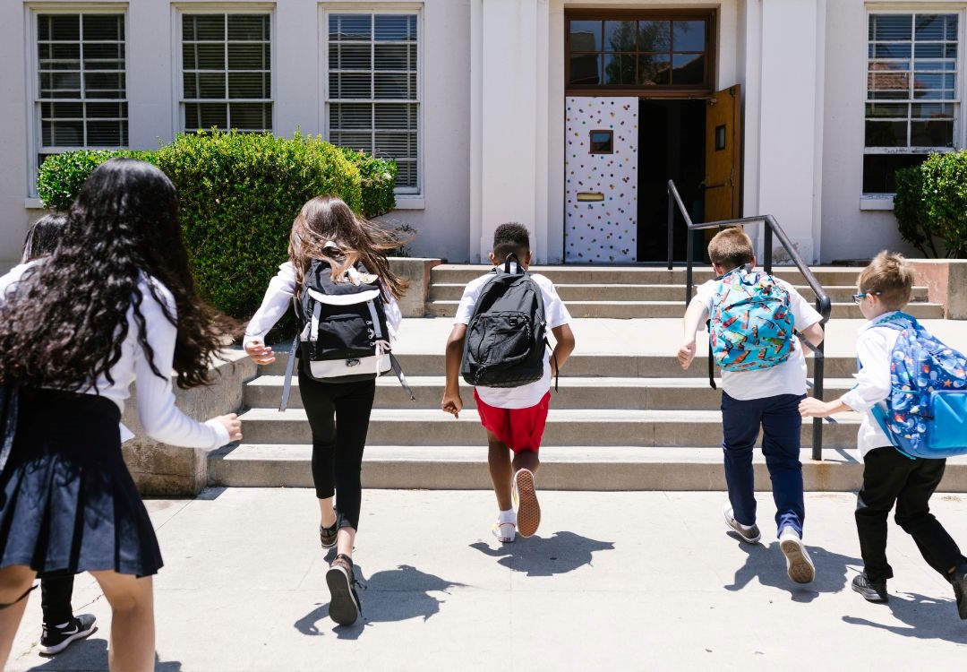 A group of students walking up the steps of a building with colorful decor on the door.