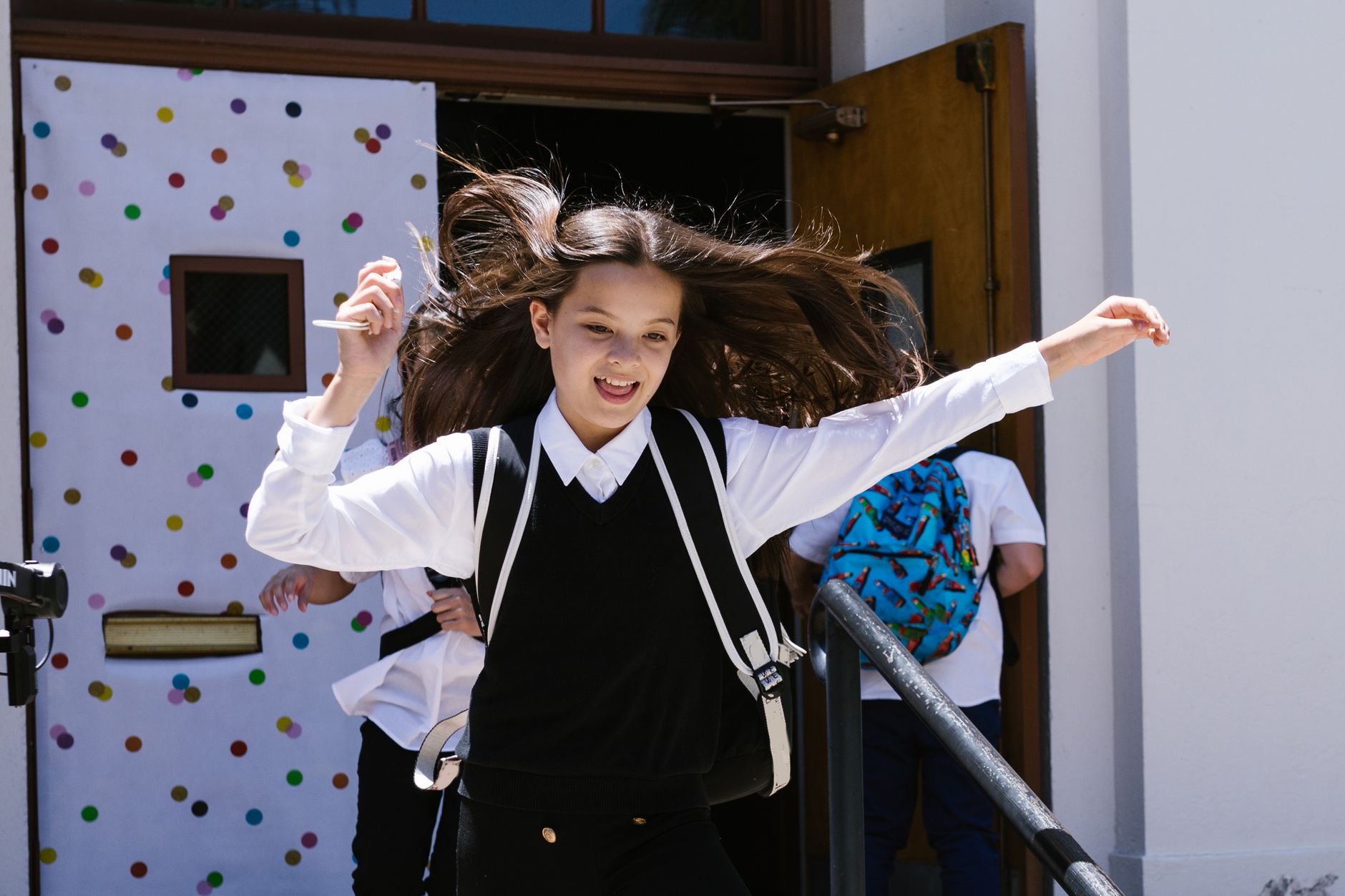 a happy girl running while wearing her school uniform